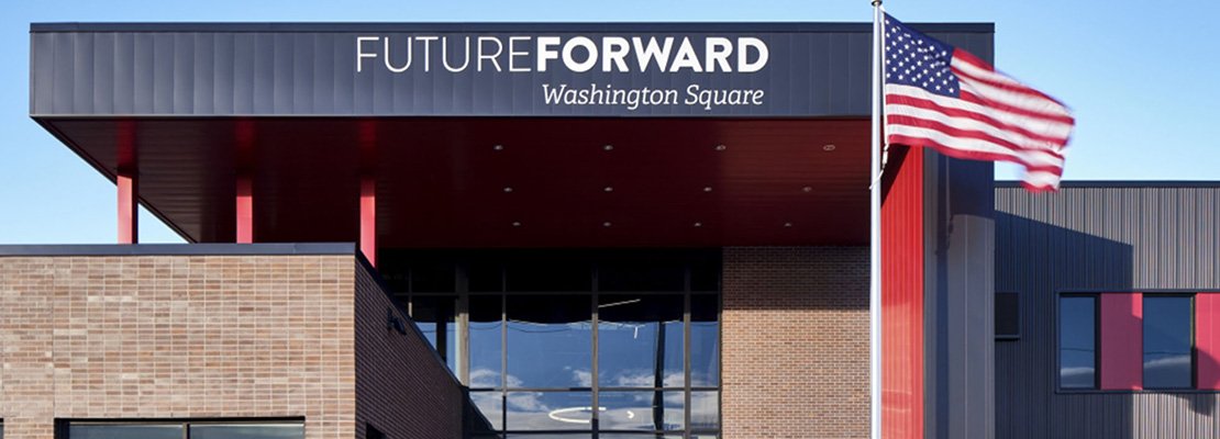 A modern building with a sign that reads FUTUREFORWARD Washington Square above the entrance. An American flag is mounted on a pole in front of the building, and the sky is clear.