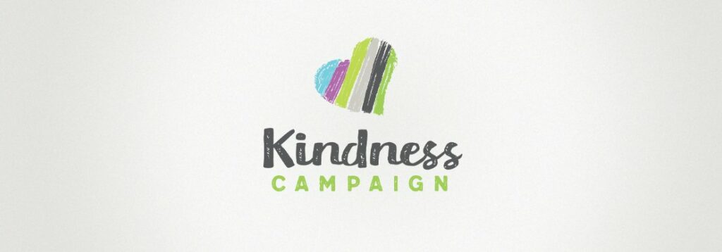 A heart shape with colorful vertical stripes above the words Kindness Campaign in a handwritten-style font, with Kindness in black and CAMPAIGN in green, on a white background.